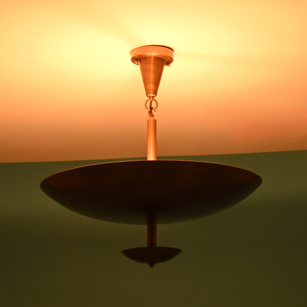 Bottom perspective of brushed brass disc chandelier with soft indirect lighting emphasizing its circular form and modern brass finish