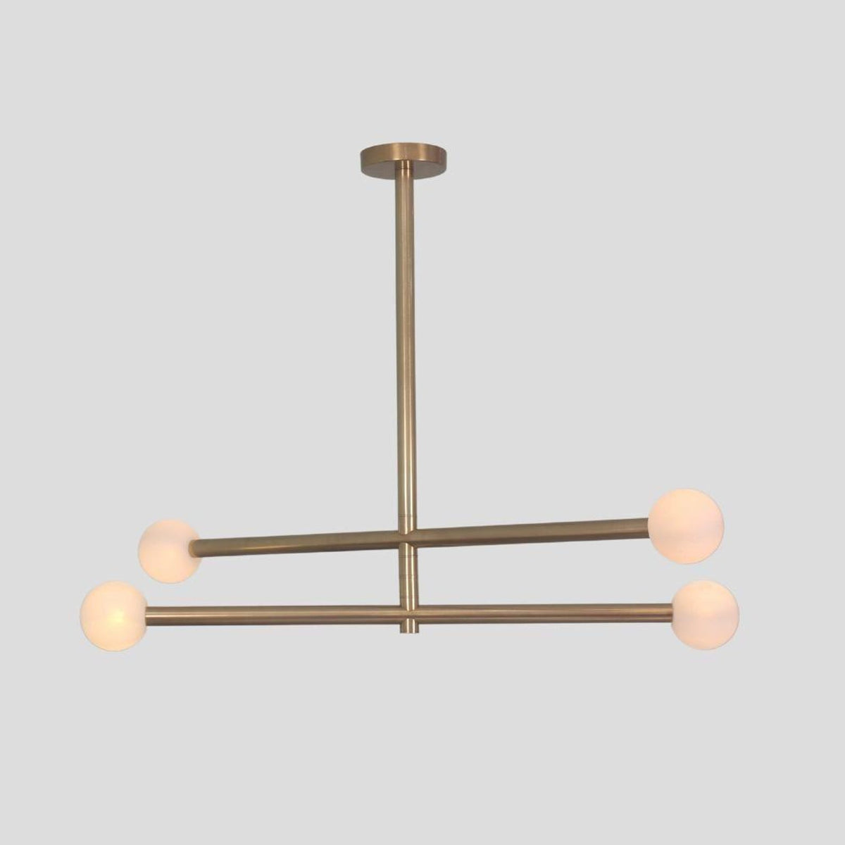 Brushed brass linear chandelier with four frosted globe shades, contemporary handmade ceiling light.