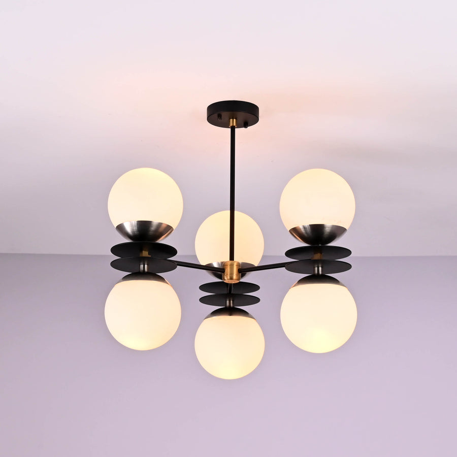 Brushed brass chandelier with six opal glass globes providing warm ambient lighting