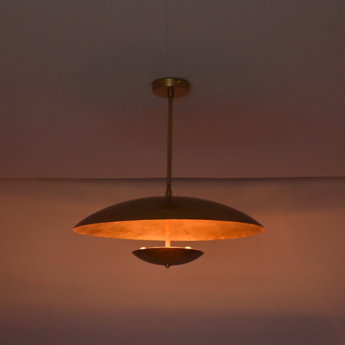 Detail view of brushed brass pendant ceiling canopy and solid brass drop rod connection.