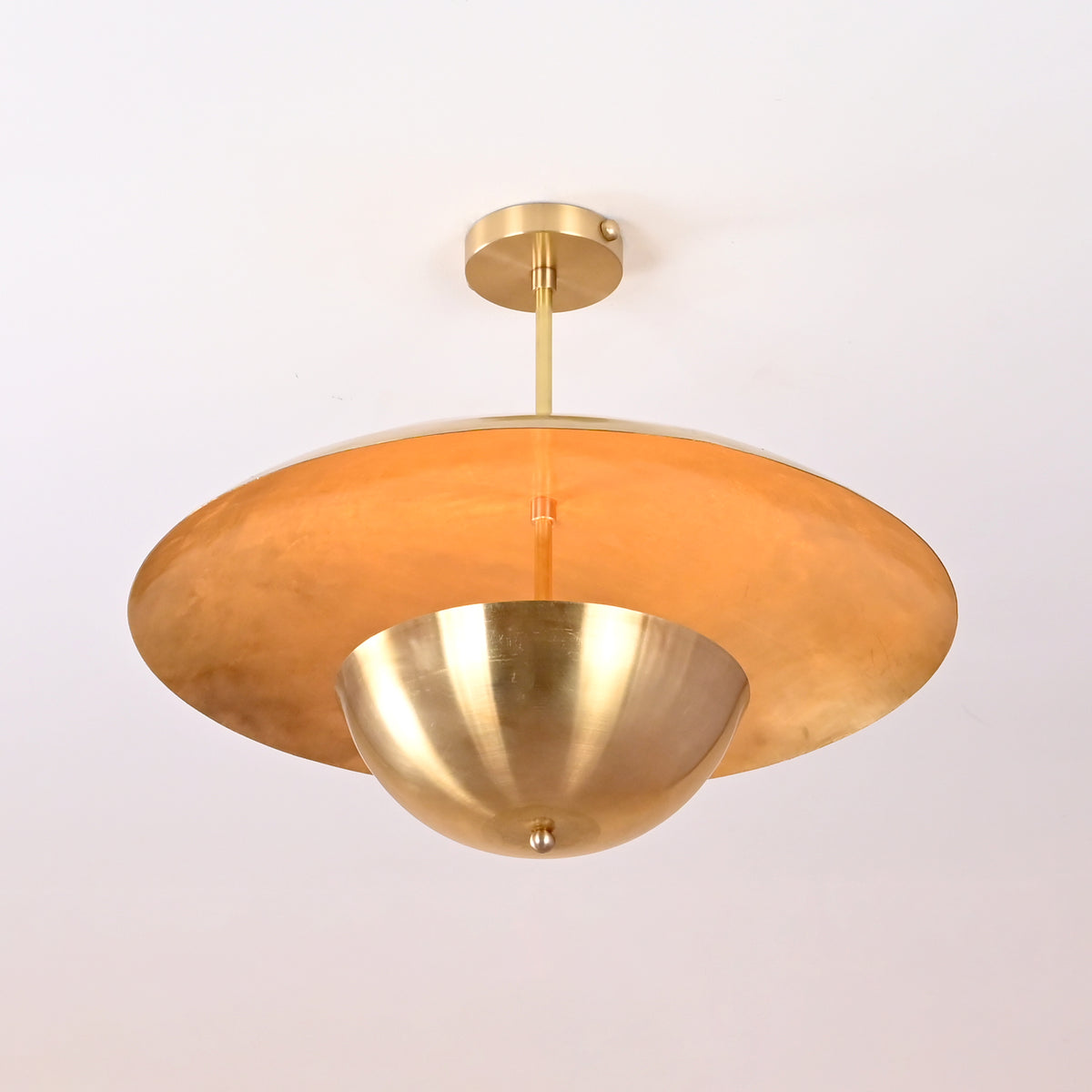 Angled view of handmade brass disc chandelier showing smooth reflective finish and balanced proportions