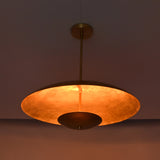 Underside view of brushed brass pendant showing warm reflected light and circular bowl form.