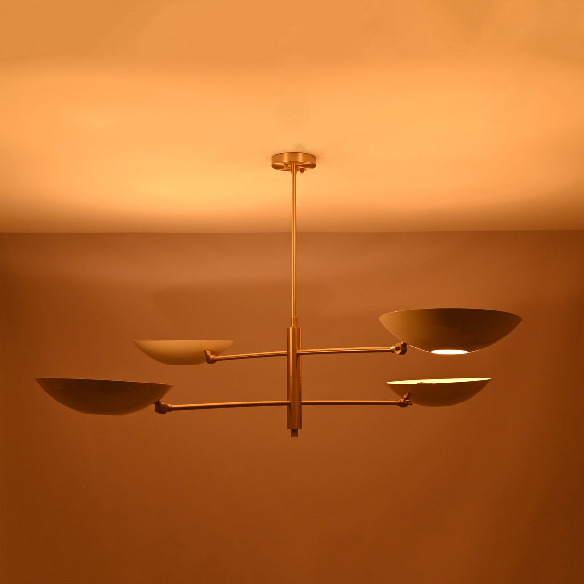 Brushed brass saucer chandelier shown from angled view with slim rods, central stem, and sculptural bowl shades