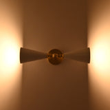 Brushed brass wall light closeup showing central sphere, arm detail, and white enamel cone shades
