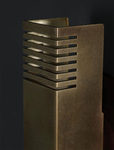 Close-up of brushed brass wall sconce showing precision slotted metal design and premium brass finish