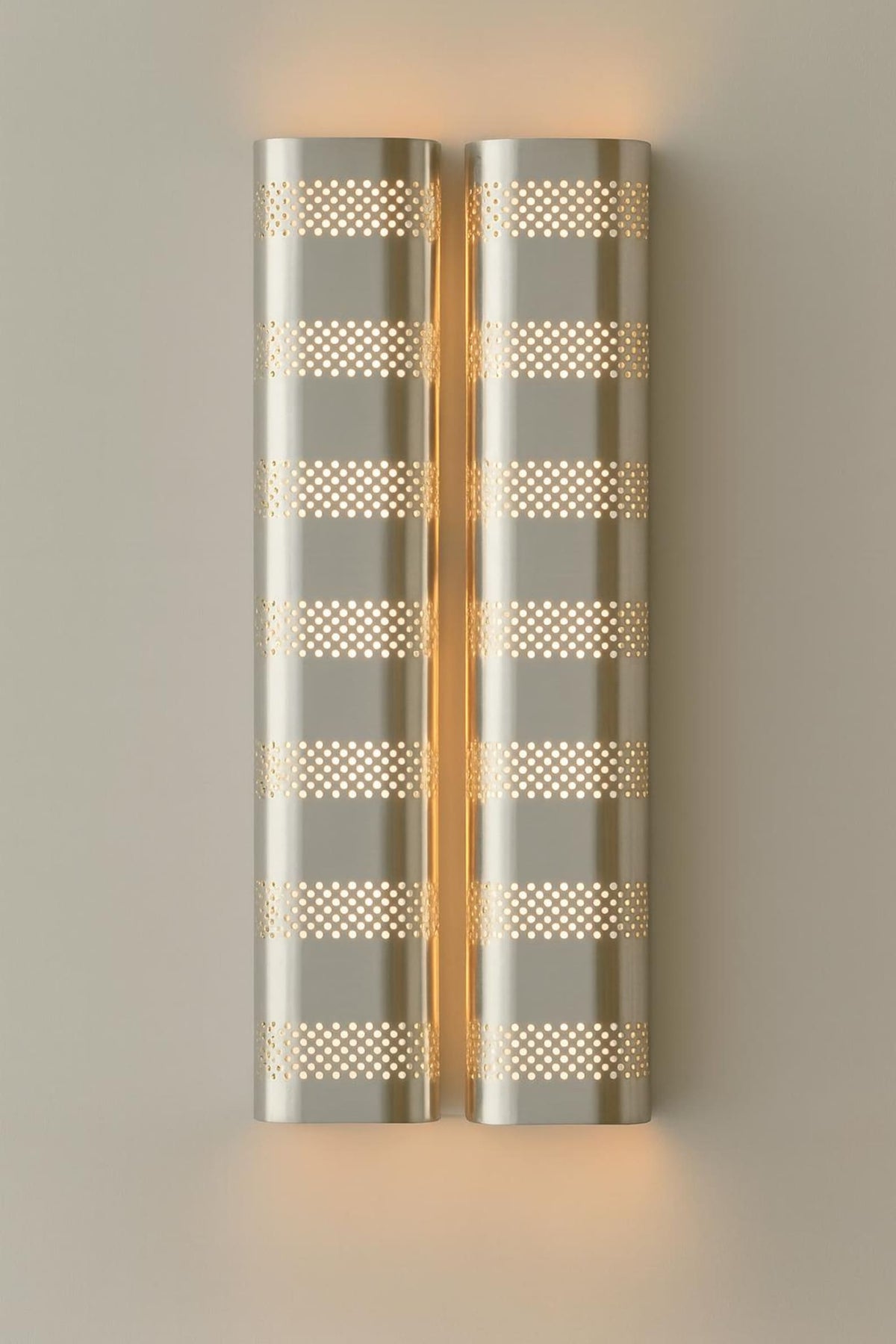Brushed chrome finish perforated brass wall sconce providing soft indirect lighting in a modern interior