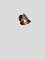 Brushed copper cone wall light illuminated with soft ambient glow, ideal for modern living rooms, hallways, and bedrooms.
