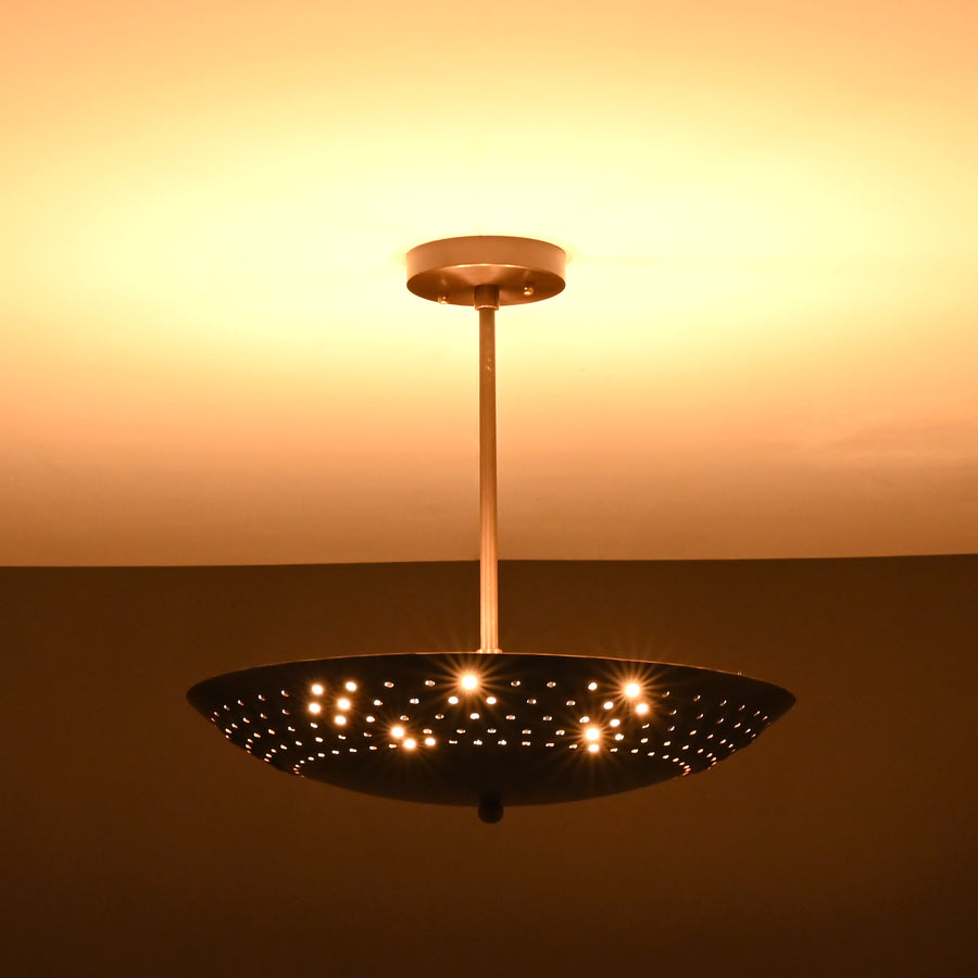 Modern living room with disc-shaped brass pendant light casting warm ambient light