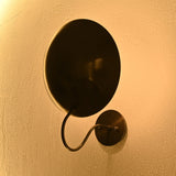 Curved disc wall sconce illuminating a contemporary hallway with soft indirect ambient light
