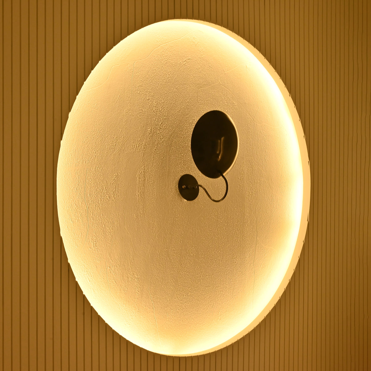 Modern blackened brass disc wall sconce used as decorative lighting in an upscale living room