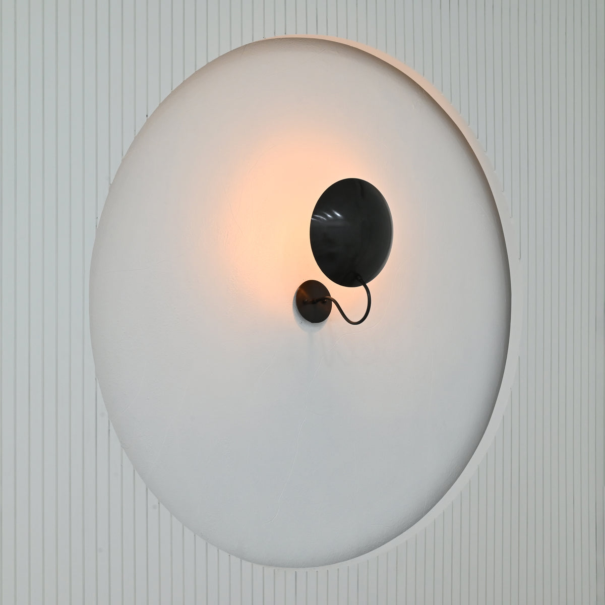 Sculptural Brussels wall light with large convex disc shade and minimalist blackened brass finish