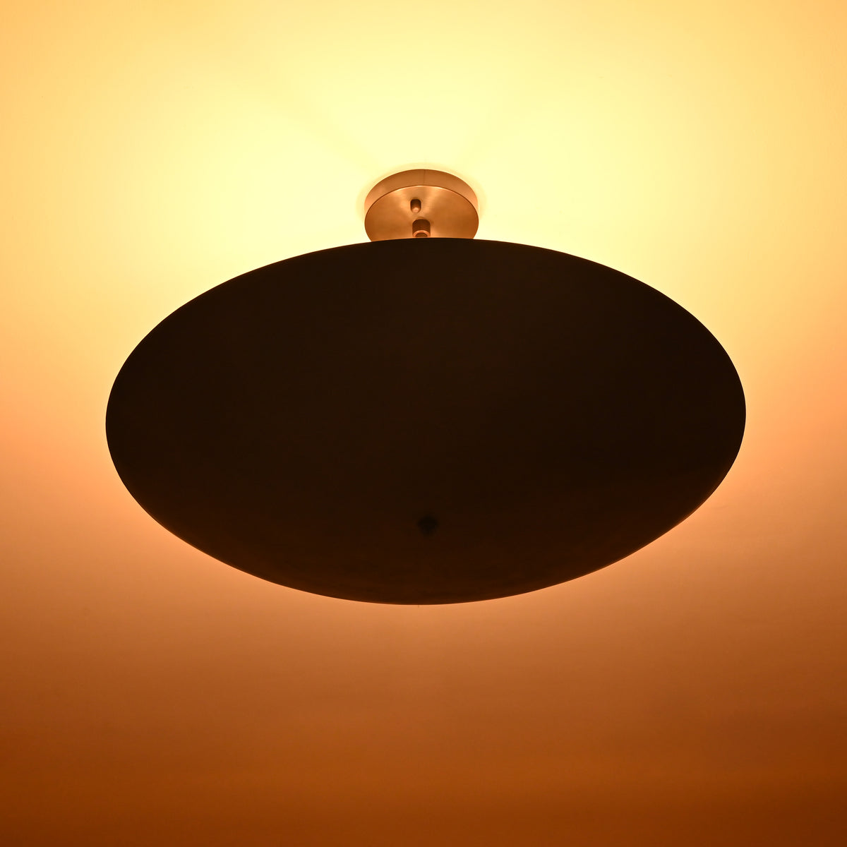 Blackened brass flushmount chandelier emitting soft warm light