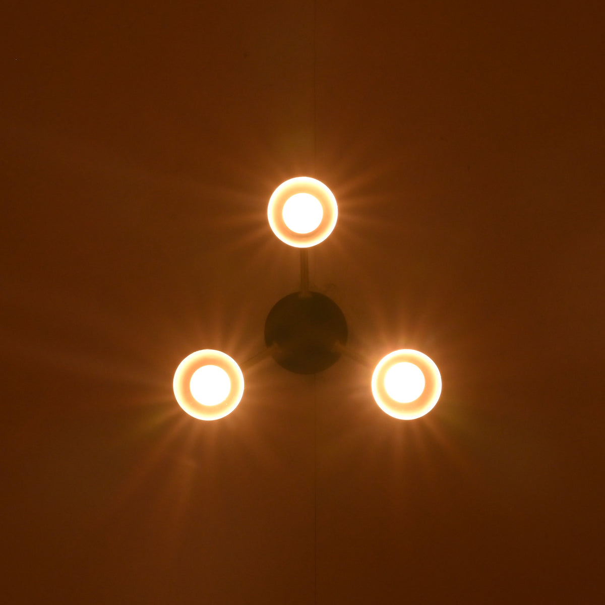 3 bulb brass and black modern ceiling light glowing warmly in evening interior setting
