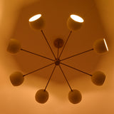 Ceiling view of handmade brass chandelier featuring eight luminous cream domes in radial design