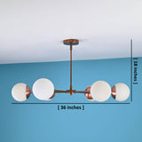 Modern brass chandelier with frosted glass globes showing 36-inch width and 18-inch height measurements against blue wall background.