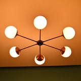 Six-light brass chandelier illuminated, creating warm ambient glow with frosted glass globes and copper accents.