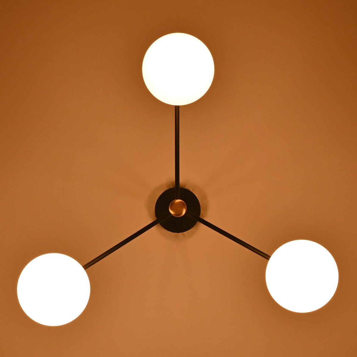 Top view of brass and black 3-light chandelier with glowing glass globes