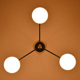 Top view of brass and black 3-light chandelier with glowing glass globes