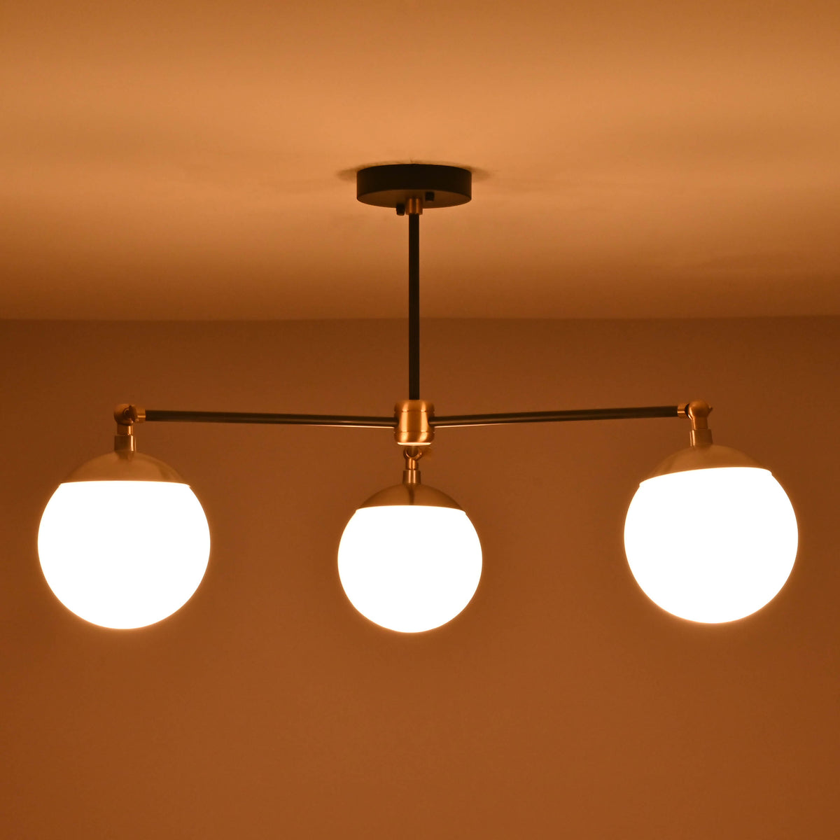 3-light brass and matte black chandelier casting warm ambient light in a room