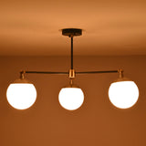 3-light brass and matte black chandelier casting warm ambient light in a room