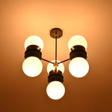 Brass and black 6-globe chandelier illuminated warmly with opal glass shades casting ambient light