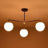 Modern brass and black flushmount chandelier glowing warmly with three globe lights
