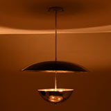Chrome bowl-and-disc pendant light producing warm indirect illumination from below