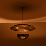 Chrome brass disc chandelier illuminated at night with warm ambient lighting and soft reflections