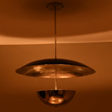 Chrome and black pendant chandelier casting moody warm lighting in dark room setting