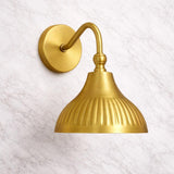 Elegant brass dome wall light with curved arm design providing soft downward illumination on neutral wall.