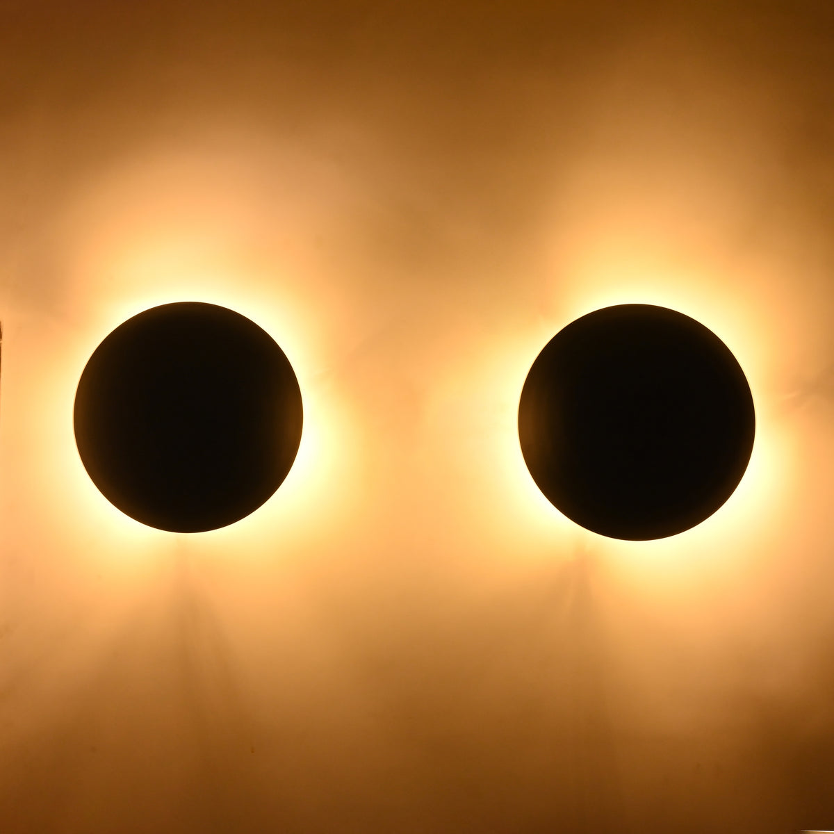 Close-up of the Eclipse matte black dome wall sconce producing a warm indirect glow that enhances modern interiors.