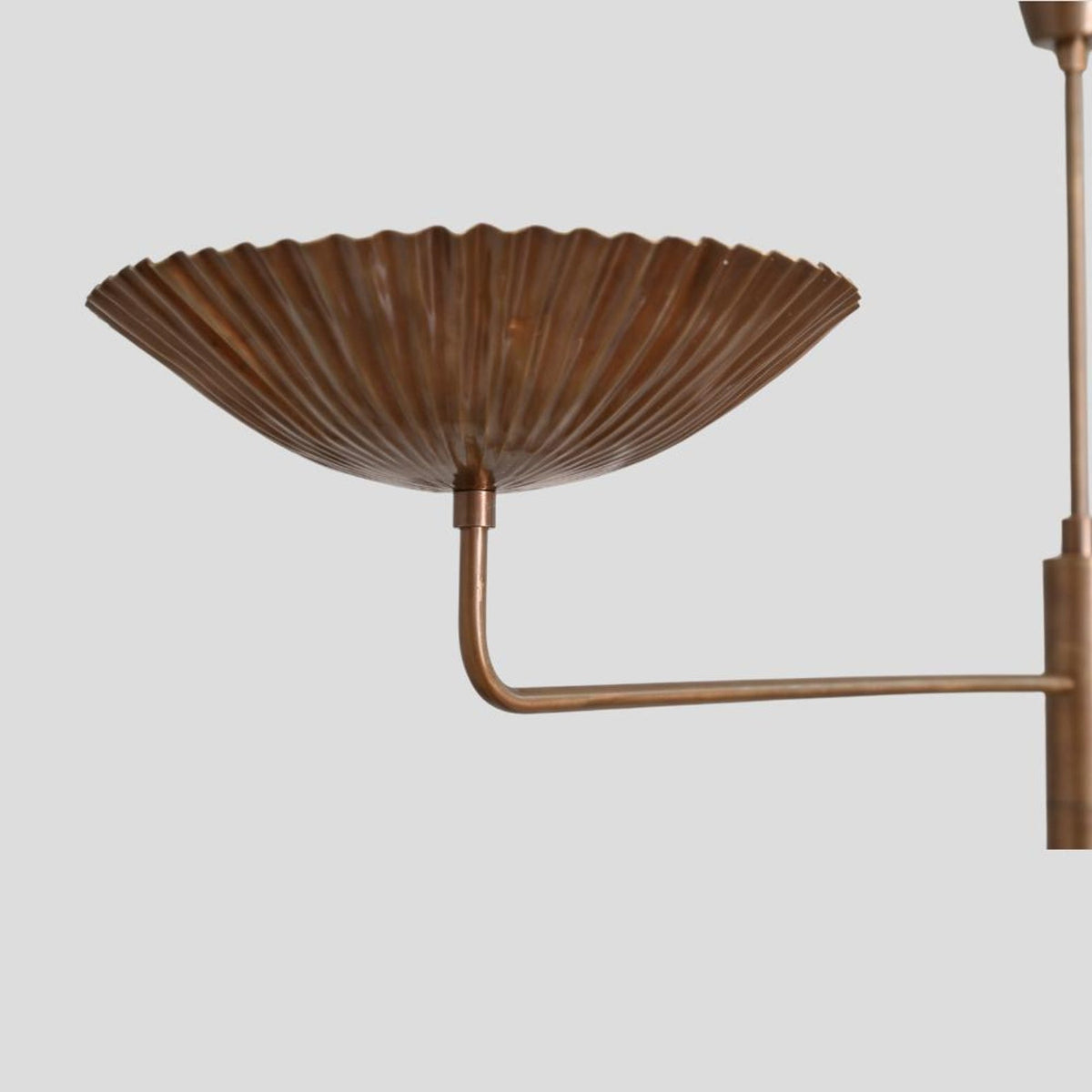 Close-up view of fluted brass bowl shade on chandelier, showcasing handmade craftsmanship and textured detailing.