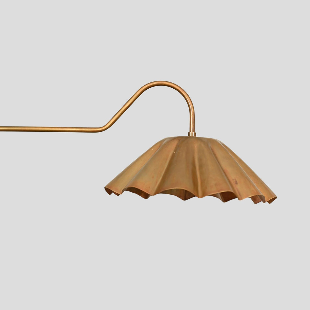 Close-up view of pleated brass bowl shade on chandelier, showcasing handmade detailing and elegant brass texture.