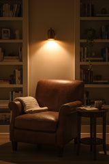 Close-up of compact cylindrical wall sconce showing rounded top, decorative finial and circular mounting plate