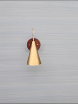 Mounted view of cone brass and wood wall light on neutral background showing refined craftsmanship and smooth brass patina.
