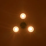 Top view of cone style brass chandelier emitting soft circular glow against dark ceiling