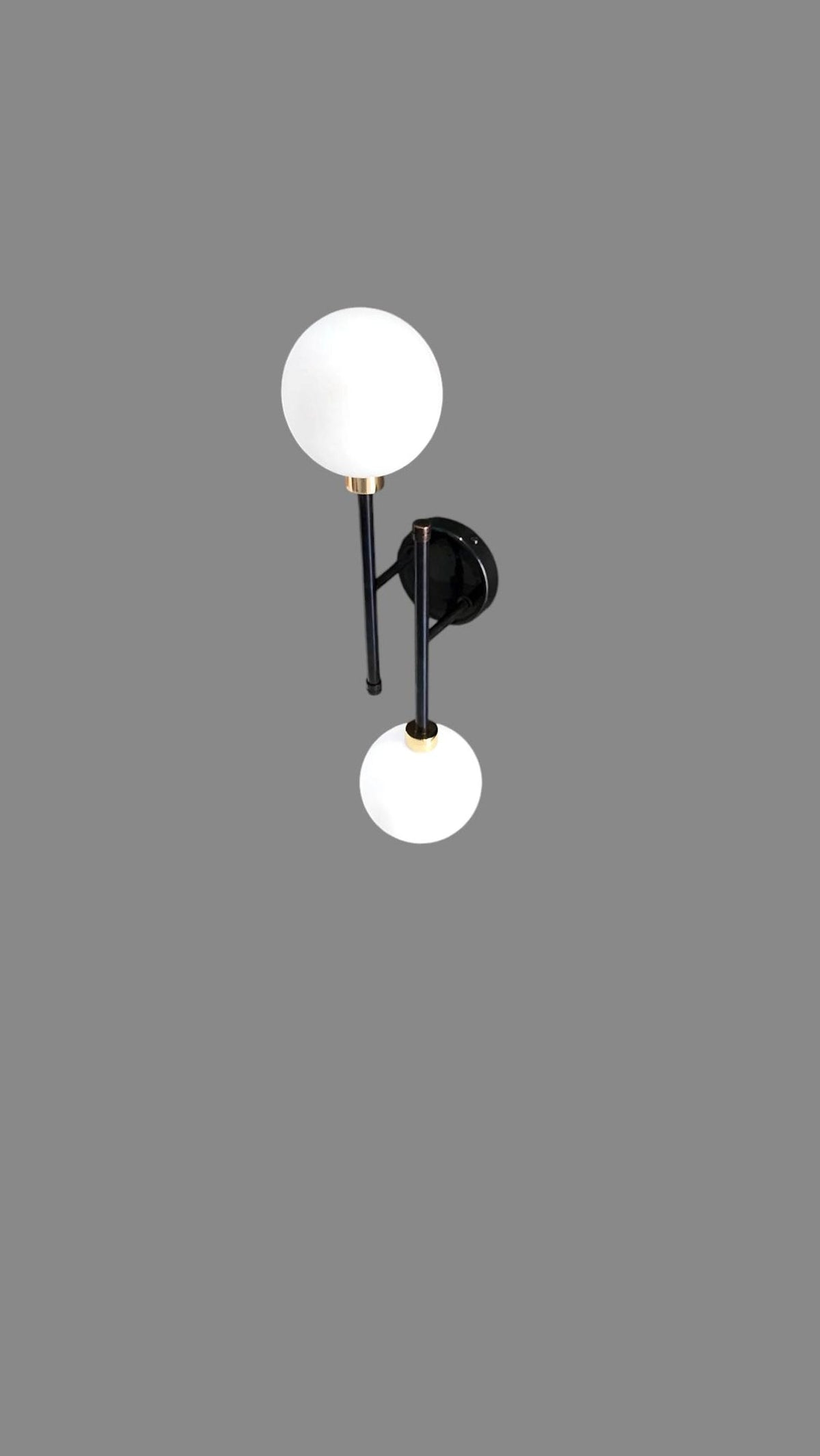 Front view of contemporary black and brass wall light featuring two frosted glass globes and minimalist vertical frame.
