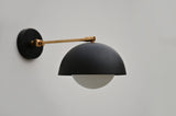 Front view of contemporary black dome wall light with brass fixture, combining industrial and minimalist design elements.
