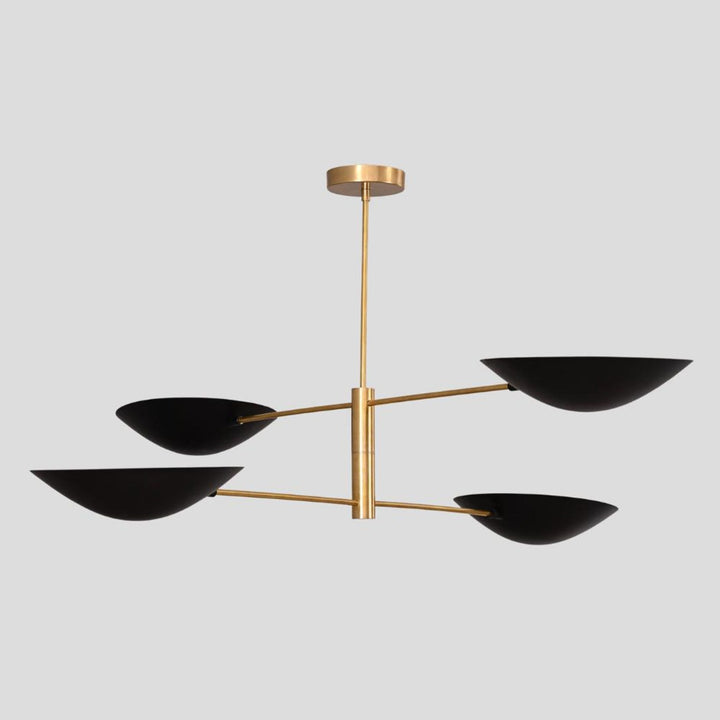 Contemporary brass chandelier featuring four sleek black bowl shades, handcrafted design for modern dining and boutique interiors.