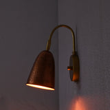 Copper hammered wall sconce brass mount glowing in dim light – warm ambient wall lighting