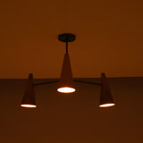 Three light copper cone chandelier in dark setting creating moody, atmospheric ceiling lighting