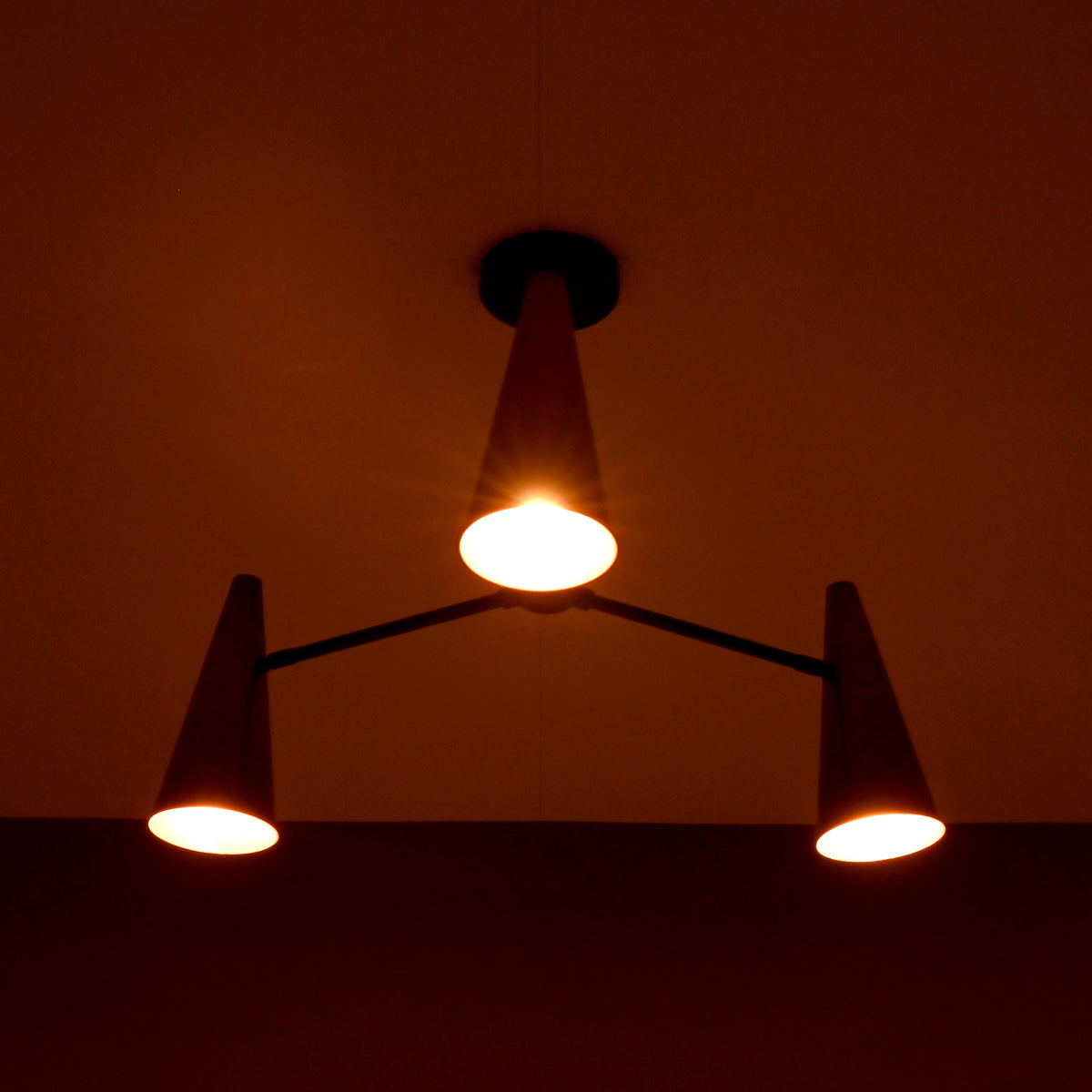 Copper cone chandelier casting warm ambient lighting for modern and industrial interiors