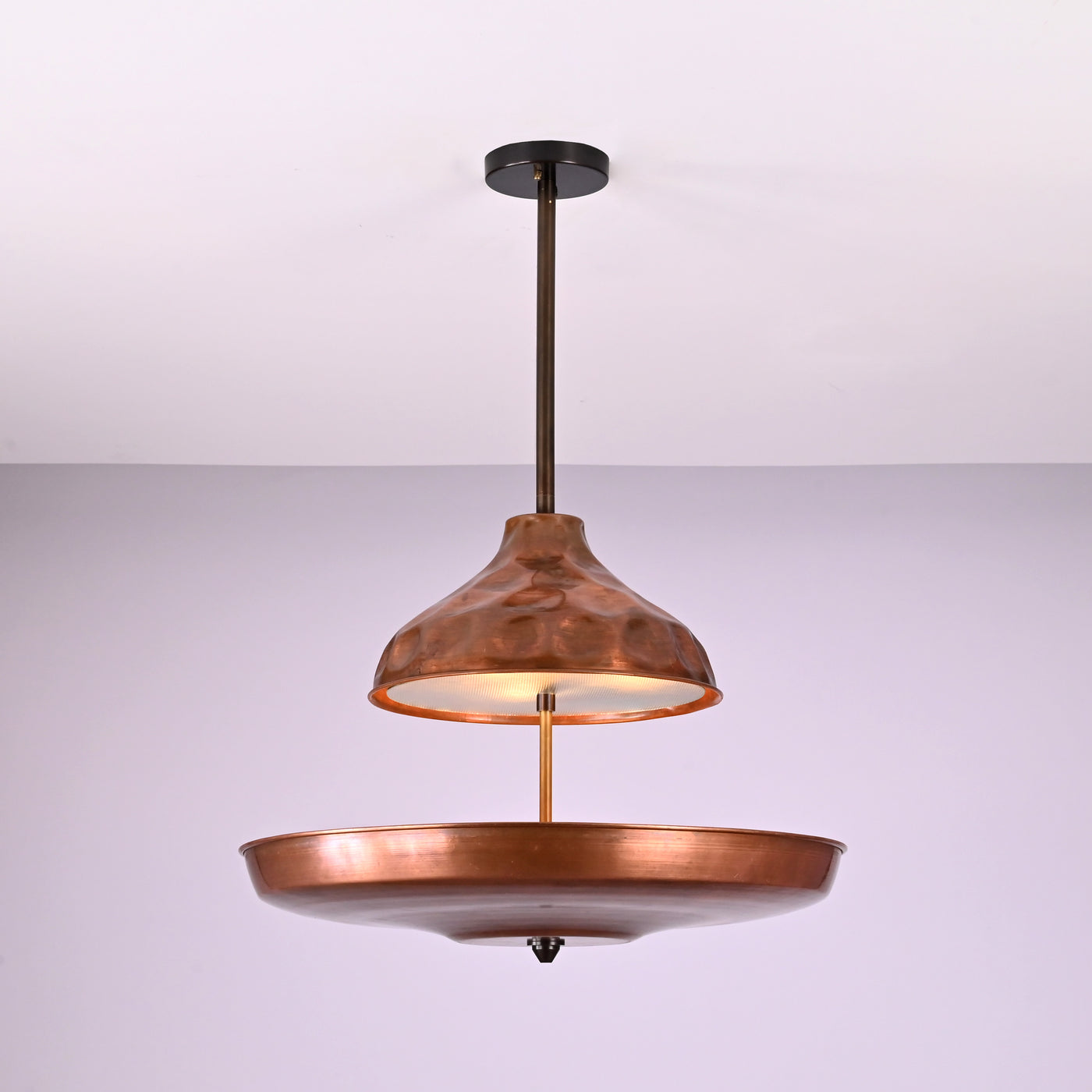Modern copper disc chandelier with warm indirect lighting and sculptural bowl shade, handcrafted from solid brass