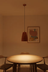 Copper pendant light hanging in a hallway with rich red patterned shade and warm focused illumination