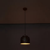 Cora pendant light glowing warmly from below, highlighting the compact drum shade and textured copper finish