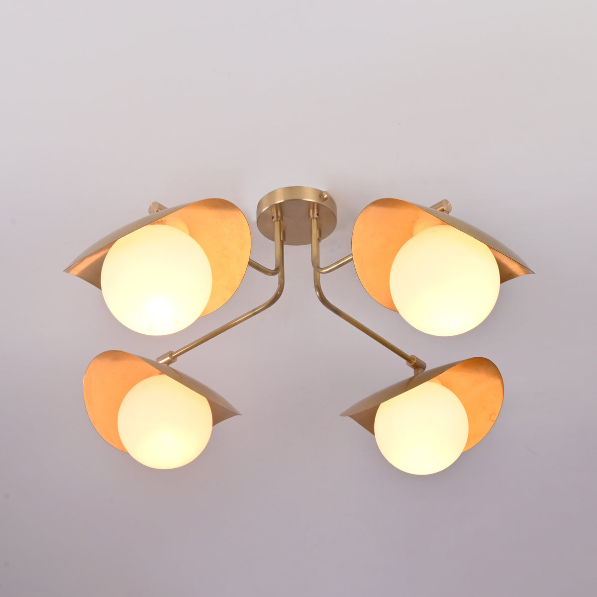 Bottom view of Curva brass flush mount revealing symmetrical globe layout and softly diffused ambient lighting.