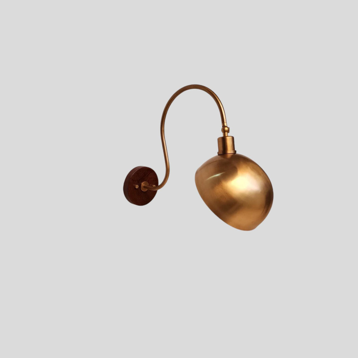 Angled view of handmade brass dome shade wall sconce with modern styling