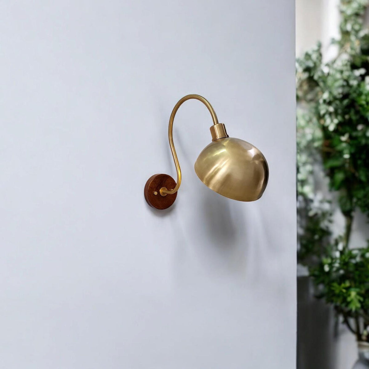 Brass dome shade wall sconce with curved arm mounted on wall interior