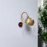 Brass dome shade wall sconce with curved arm mounted on wall interior