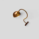 Overhead angle of brass dome shade wall sconce with curved arm design